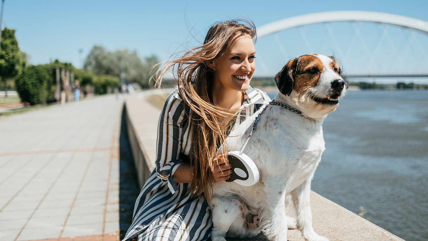 Una mujer está sentada al borde de un río junto a su perro